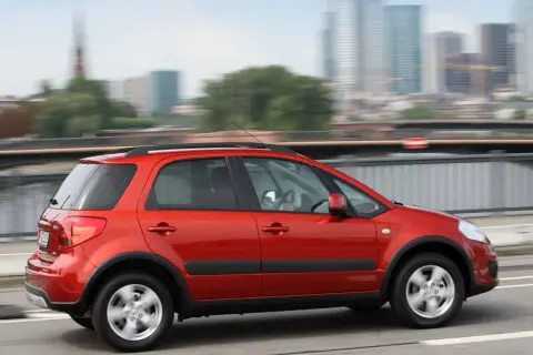 Czerwony Suzuki SX4 w ruchu miejskim. Wiele osób chwali ten model, a jego opinie są pozytywne.