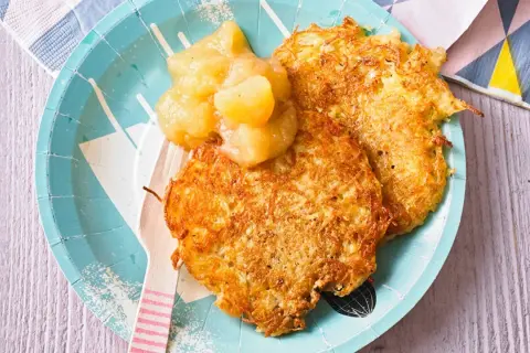Zwei knusprige Kartoffelpuffer mit Apfelmus, ein herzhaftes Gericht, das an Omas Küche erinnert.