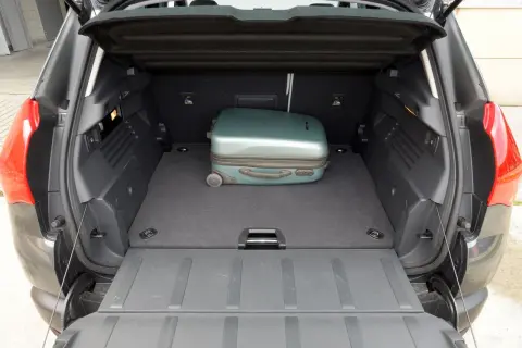 Otwarty bagażnik Peugeot 3008 z jednym zielonym walizką.