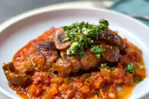 Herzhaftes Ossobuco mit einer reichhaltigen Tomaten-Gemüse-Sauce und frischer Kräuter-Gremolata als Beilage.