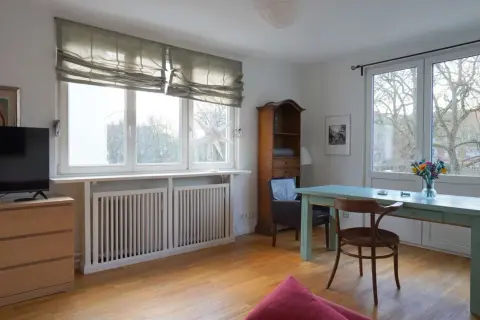 Gemütliche schlafnische im wohnzimmer mit TV, Bücherregal und Esstisch. Große Fenster lassen viel Licht herein.
