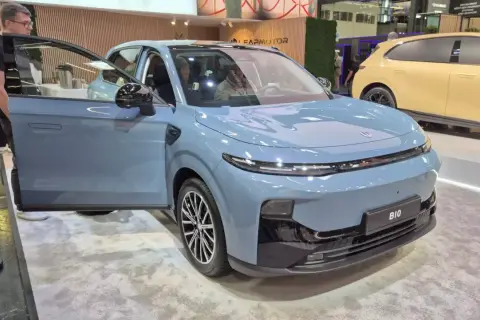Niebieski SUV z otwartymi drzwiami, prezentujący nowoczesny typ nadwozia. Obok stoi żółty samochód.