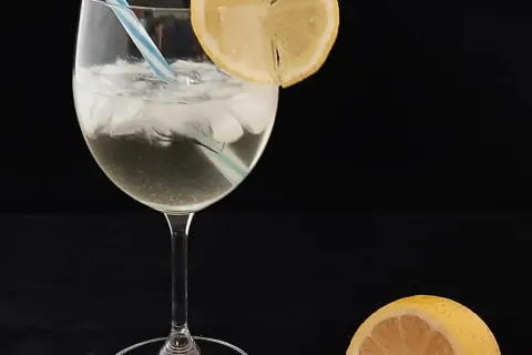Un verre de spritz saint germain, glacé et garni d'une tranche de citron, prêt à être dégusté.