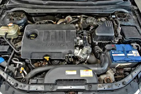 Silnik Kia Ceed 1.6 CRDi. Widoczny jest czarny plastikowy kolektor, akumulator Bosch i zbiornik płynu chłodniczego.