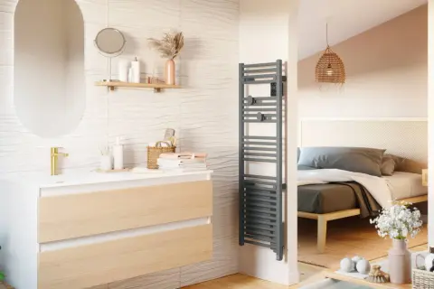 Salle de bain moderne avec meuble vasque, miroir ovale et sèche serviette gris. La puissance du sèche serviette assure des serviettes chaudes.