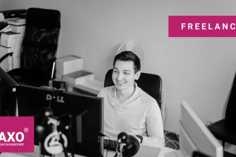 Uśmiechnięty freelancer przy biurku z komputerami. Czy freelancer musi mieć działalność gospodarczą? Zapytaj TAXO.