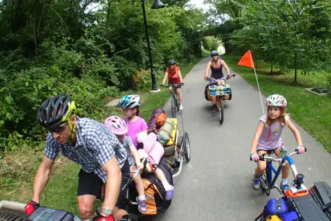 Familia disfrutando de rutas en bici con niños, remolcando equipaje y con niños pedaleando.