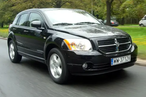 Czarny Dodge Caliber w ruchu, na mokrej drodze. Wiele osób szuka dodge caliber opinie, ten samochód wygląda na solidny.