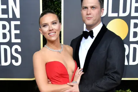 Scarlett Johansson w czerwonej sukni i Colin Jost w garniturze na ściance Golden Globe Awards.