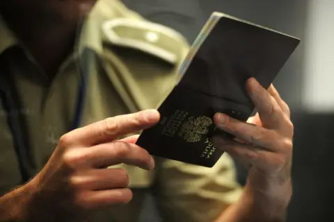 Dłonie trzymają otwarty polski paszport. Czy trzeba oddać stary paszport? Urzędnik sprawdza dokument.