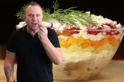 Mężczyzna degustuje warstwową sałatkę, która wygląda jak śledzie pod pierzynką. Przepis na tę pyszną potrawę jest w zasięgu ręki!