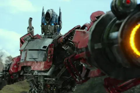 Optimus Prime, przywódca Autobotów, z niebieskimi oczami i płonącą bronią, gotowy do walki.