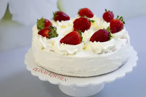 En krämig tres leches-tårta med vispgrädde och färska jordgubbar, perfekt för ett sommarfika.