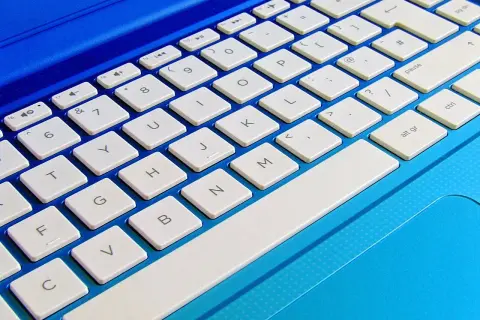 Niebieski laptop z białymi klawiszami. Dowiedz się, jak podłączyć klawiaturę do laptopa, aby ułatwić sobie pisanie.