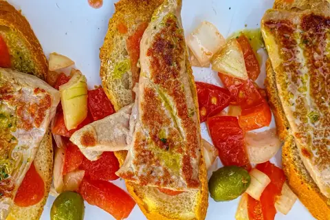Delicioso tapeo en el ejido: tostadas con pescado a la plancha, pimientos, tomate y aceitunas.