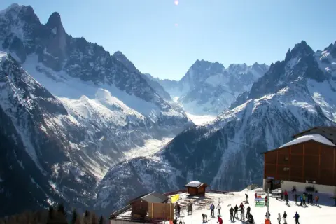 Magnifique paysage de montagne enneigée, idéal pour un week-end à Chamonix. Des skieurs profitent du soleil et des pistes.