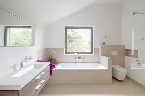 Salle de bain moderne avec baignoire, lavabo et WC suspendu. La séparation salle de bain avec wc est subtile, créant un espace fluide et lumineux.