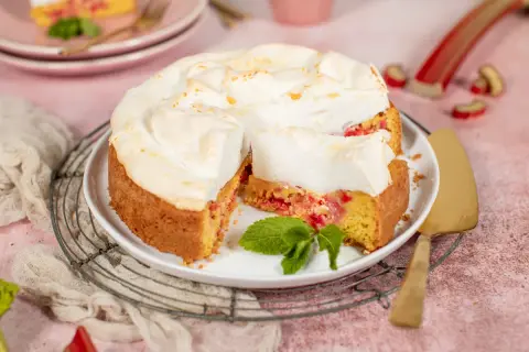 Saftiger Rhabarberkuchen mit luftigem Baiser, garniert mit frischer Minze. Ein Genuss für jeden Kaffeetisch.