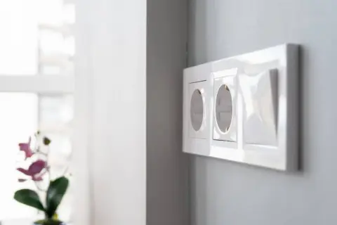 Instalación eléctrica moderna: cómo poner un enchufe donde no hay. Dos tomas de corriente y un interruptor en una pared gris.