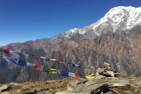 Vackra böneflaggor fladdrar i vinden under en snöklädd bergstopp. En oförglömlig upplevelse av att vandra i Nepal.