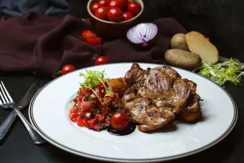 Soczysty udziec wołowy z salsą pomidorową i ziemniakami.
