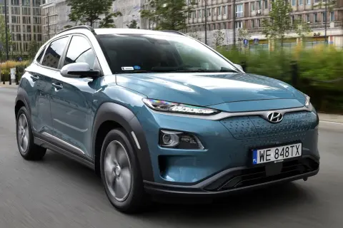 Niebieski Hyundai Kona na drodze, z widocznymi detalami, które mogą być brane pod uwagę jako **hyundai kona wady**, np. nietypowy design przedniego grilla.