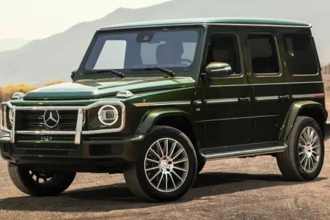 Un imponente Mercedes-Benz verde oscuro, el mejor Mercedes del mundo, se detiene en un camino polvoriento con montañas al fondo.
