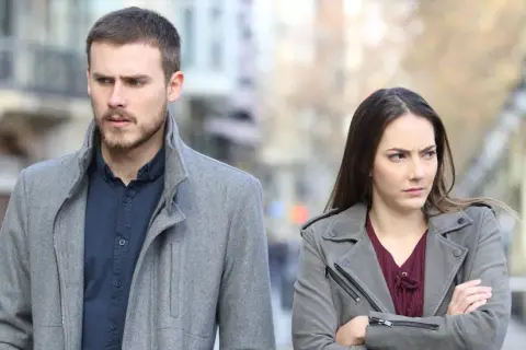 Een man en vrouw lopen met een boze blik uit elkaar. Ze lijken conflict zoekende mensen, elk met hun eigen gedachten.