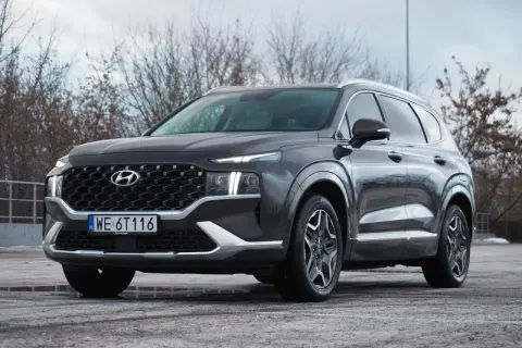 Ciemnoszary Hyundai Santa Fe z polskimi tablicami WE 6T116 stoi na parkingu.