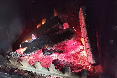 Braises rougeoyantes et flammes bleues dans un feu de bois, la chaleur monte.