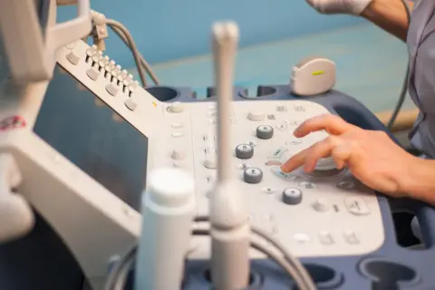 Dłoń naciska przyciski na aparacie USG. To urządzenie pozwala zobaczyć wnętrze ciała, co oznacza fl usg.