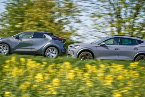 Dwa szare samochody, Toyota i Cupra, pędzą przez kwitnące pole rzepaku.