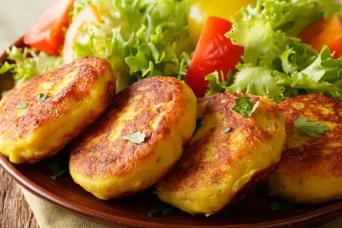 Goldbraune Kartoffelpuffer, nach Omas Kartoffelpuffer Rezept mit gekochten Kartoffeln, serviert mit frischem Salat.