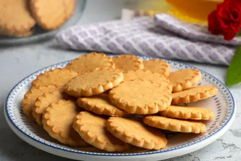Stos pysznych, szybkich ciasteczek maślanych na talerzu z niebieskim wzorem. Idealne na podwieczorek.