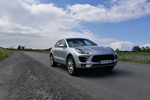 Srebrny Porsche Macan na drodze. To właśnie Porsche produkuje te luksusowe SUV-y.
