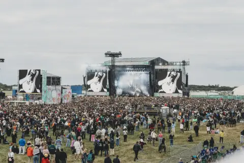 Tłum ludzi na festiwalu, wielka scena z ekranami pokazującymi gitarę. To zapewne opener 2024 lineup.