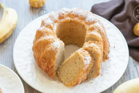 Reife Bananen verwerten: Ein saftiger Bananenkuchen mit Puderzucker bestäubt, daneben liegen frische Bananen.