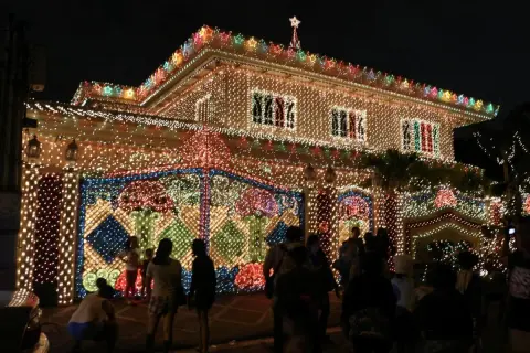 Ein Haus auf den Philippinen, das mit Tausenden von Lichtern für Weihnachten geschmückt ist. Die Fassade und der Zaun leuchten hell.