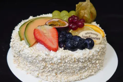 En vacker tårta, perfekt för att dekorera tårta med frukt. Toppad med melon, jordgubbar, blåbär, passionsfrukt och vindruvor.