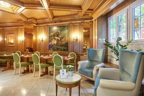 Elegancka jadalnia w hotelu Murat z zielonymi krzesłami i obrazem konnym.
