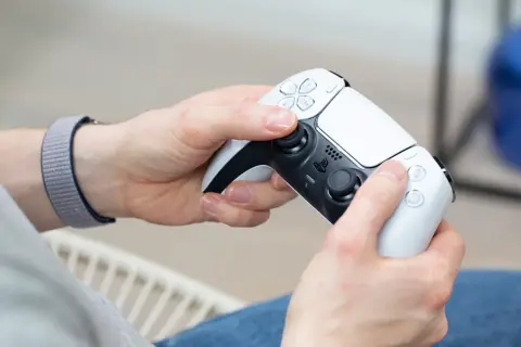 Hände halten einen weißen PS5-Controller, bereit für das PS4 auf PC streamen.