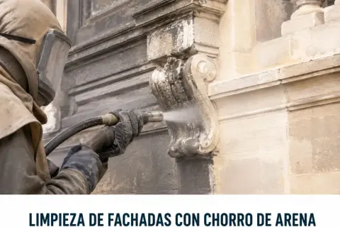 Restauración de fachadas con limpieza a chorro de arena. Un operario con equipo de protección limpia detalles ornamentales de piedra.