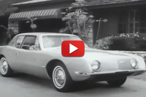 En Studebaker Avanti glider framför ett hus.