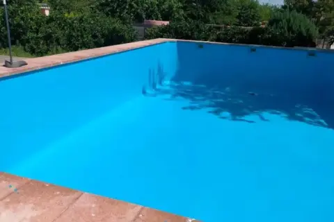 Piscina vacía con paredes pintadas de azul brillante, mostrando que se puede pintar una piscina encima del gresite.