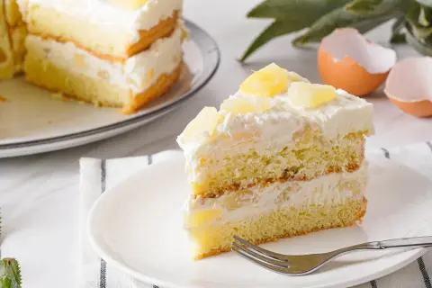Ein saftiges Stück Ananas Torte mit Sahne und Ananasstücken, bereit zum Genießen.