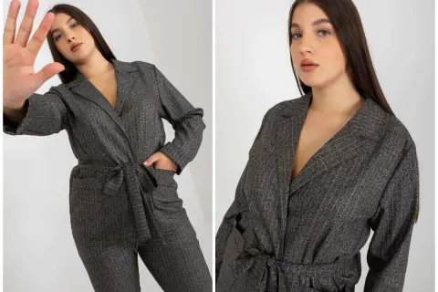 Eleganckie garnitury damskie plus size w prążki. Modelka prezentuje stylowy kombinezon z paskiem.