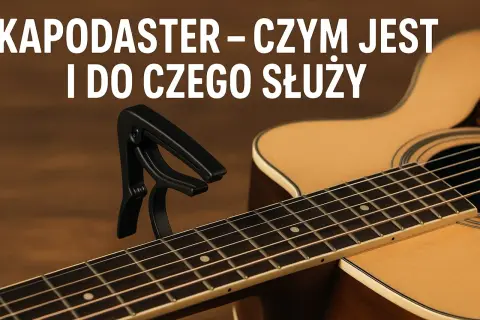 Czarny kapodaster na gryfie gitary akustycznej. Dowiedz się, kapodaster co to i jak ułatwia grę.