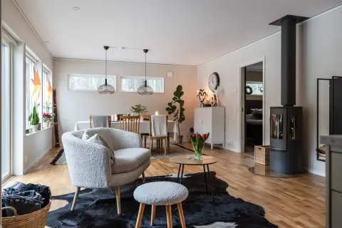 Ett mysigt vardagsrum med en fluffig fåtölj, en kamin och en matplats.