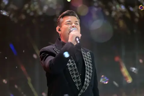 Artysta w czarnym fraku z błyszczącymi zdobieniami śpiewa, a jego zielone oczy zdają się mówić: "akcent przez twe oczy zielone tekst".