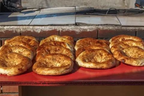 Świeżo upieczone pieczywo gruzińskie, różne rodzaje, z czarnuszką, kuszą apetycznym wyglądem.